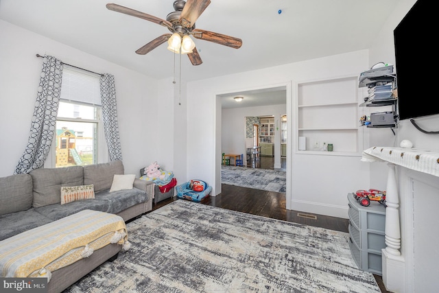 living room featuring baseboards, a ceiling fan, and wood finished floors