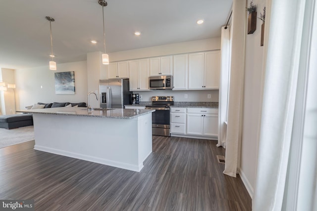 kitchen featuring dark wood-style flooring, open floor plan, white cabinetry, a sink, and appliances with stainless steel finishes