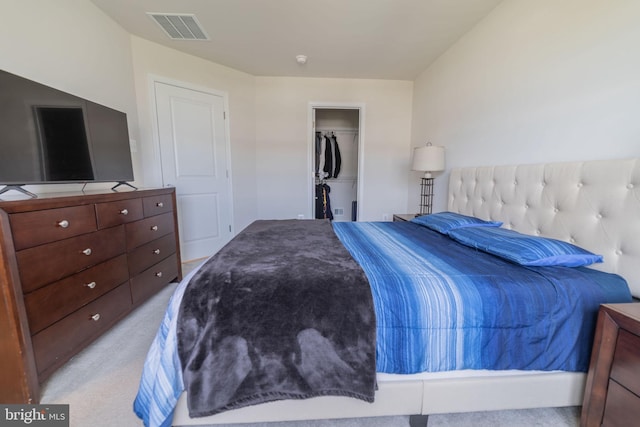 bedroom with light colored carpet, visible vents, a spacious closet, and a closet