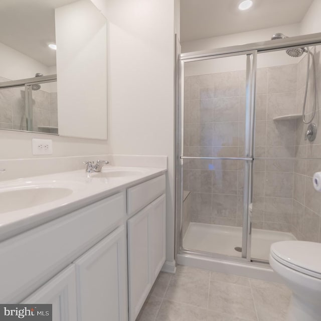 full bath featuring double vanity, a shower stall, a sink, tile patterned floors, and toilet