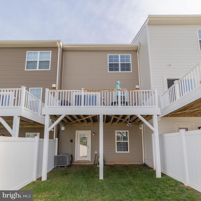 rear view of house with fence, central AC unit, a lawn, and a deck