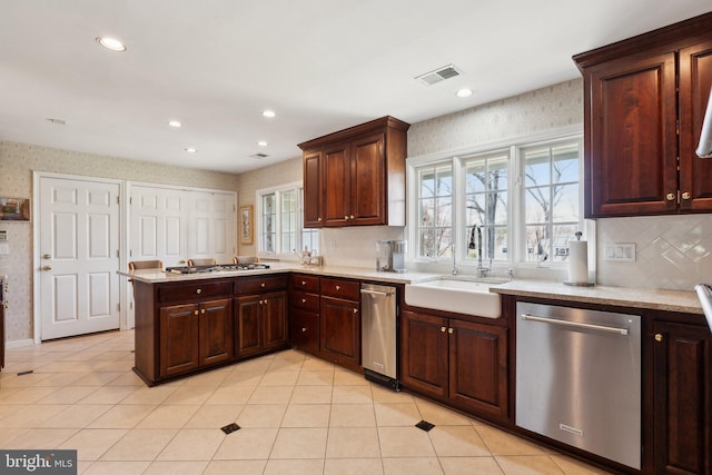kitchen featuring a sink, appliances with stainless steel finishes, a wealth of natural light, and a peninsula