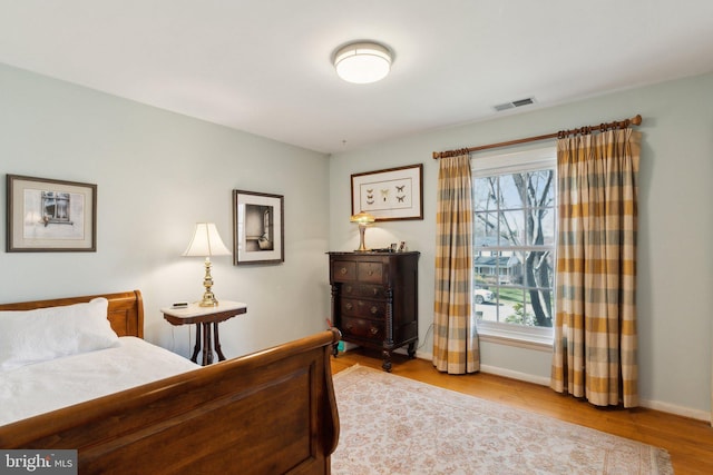 bedroom featuring visible vents, baseboards, and wood finished floors