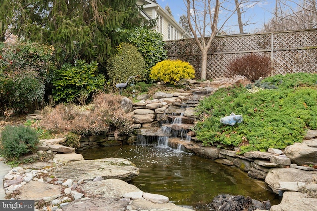 view of yard with a small pond and fence