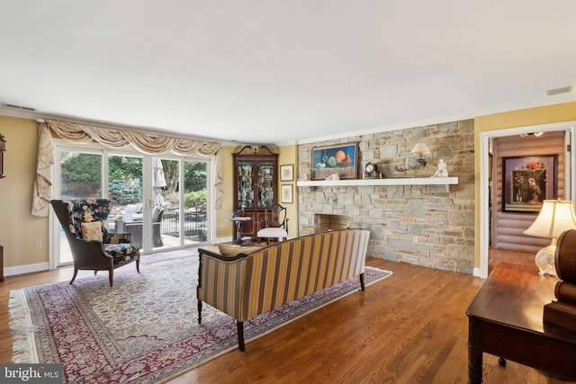 living room with crown molding, baseboards, visible vents, and wood finished floors