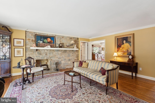 living area with crown molding, baseboards, wood finished floors, and a fireplace
