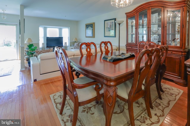 dining space featuring light wood-style flooring and a notable chandelier