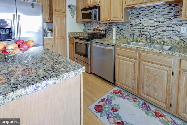 kitchen featuring decorative backsplash, light brown cabinetry, light wood-type flooring, a sink, and appliances with stainless steel finishes