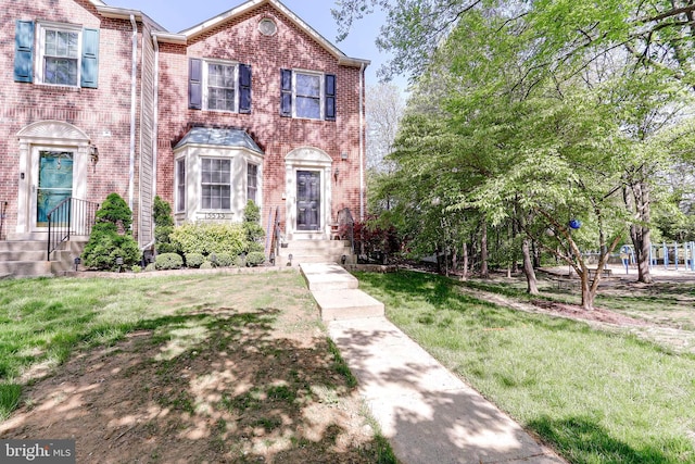 view of front of property with brick siding, a front yard, and entry steps