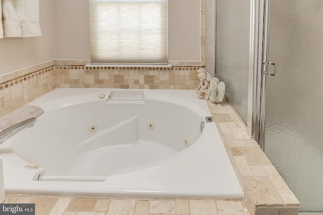 bathroom with a shower stall and a tub with jets