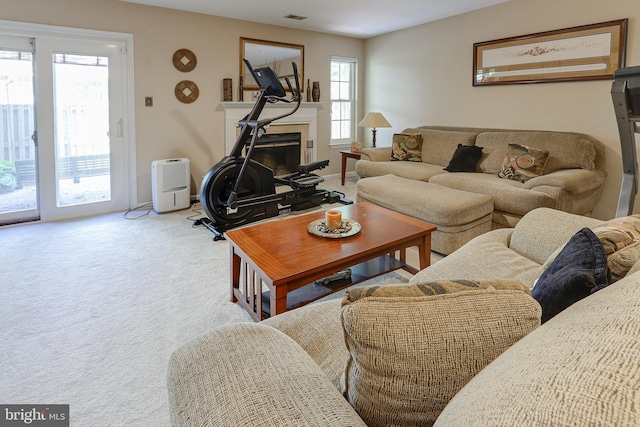 living area featuring visible vents, carpet flooring, and a glass covered fireplace