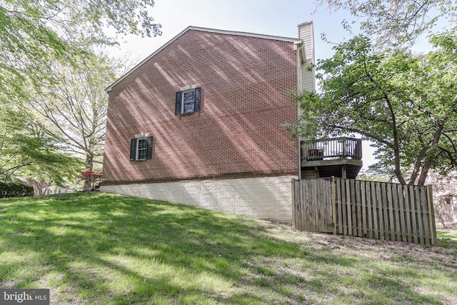view of property exterior with a chimney, a yard, and brick siding