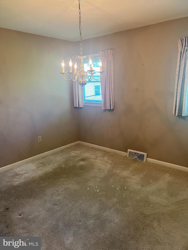 empty room with carpet floors, baseboards, a chandelier, and visible vents