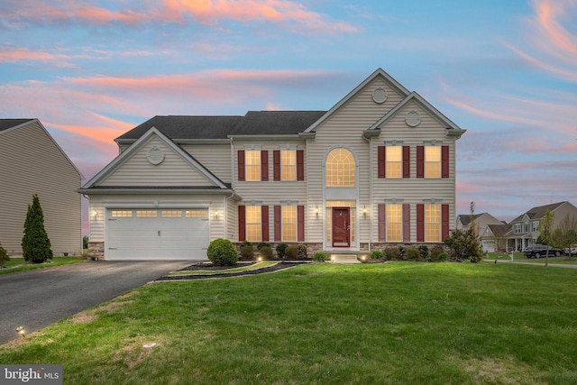 view of front of house with an attached garage, a front lawn, driveway, and stone siding