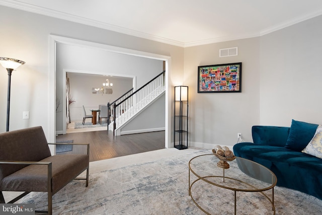 living room featuring an inviting chandelier, stairs, wood finished floors, visible vents, and ornamental molding
