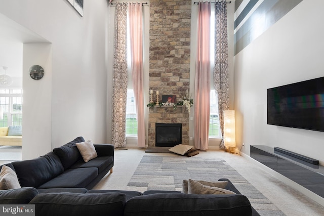 carpeted living room featuring a fireplace, a healthy amount of sunlight, and a towering ceiling
