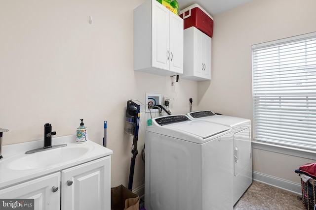 clothes washing area featuring independent washer and dryer, baseboards, a sink, and cabinet space