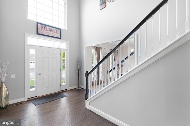 foyer with baseboards, a high ceiling, and wood finished floors