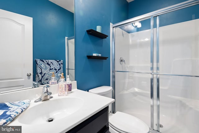 bathroom featuring vanity, toilet, and a shower stall