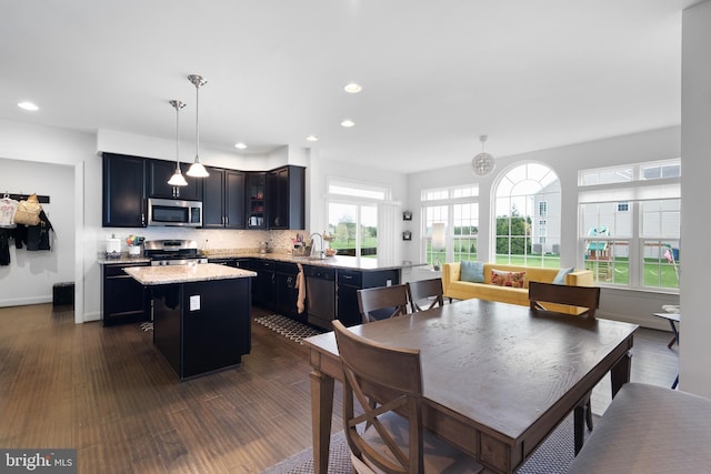 kitchen featuring decorative backsplash, a kitchen island, appliances with stainless steel finishes, recessed lighting, and dark wood-type flooring