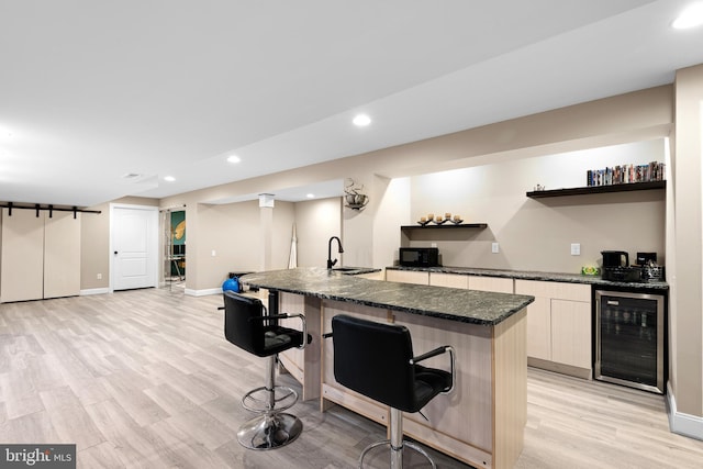 kitchen featuring open shelves, black microwave, a breakfast bar area, light wood-type flooring, and wine cooler