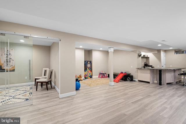 recreation room featuring baseboards, recessed lighting, light wood-style flooring, and bar