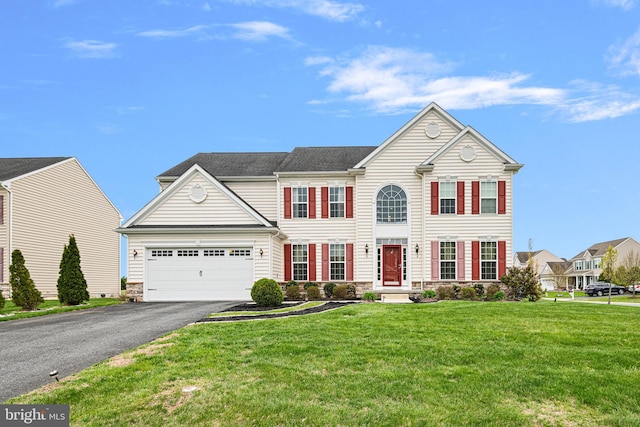 colonial home with a front yard, driveway, stone siding, and a garage