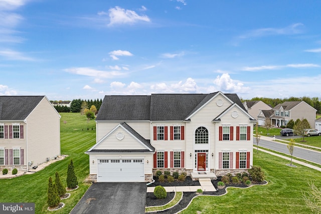 view of front facade with a front lawn, stone siding, and aphalt driveway