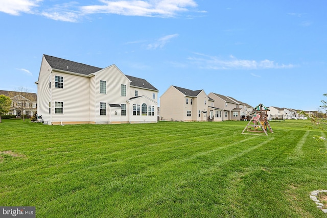 back of house featuring a lawn, a residential view, and a playground