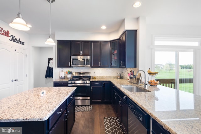kitchen with a sink, light stone counters, stainless steel appliances, and dark wood finished floors