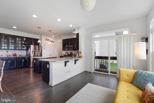 kitchen featuring glass insert cabinets, appliances with stainless steel finishes, decorative backsplash, and a peninsula