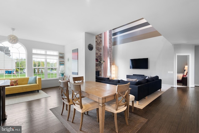 dining space with baseboards, a glass covered fireplace, and wood finished floors