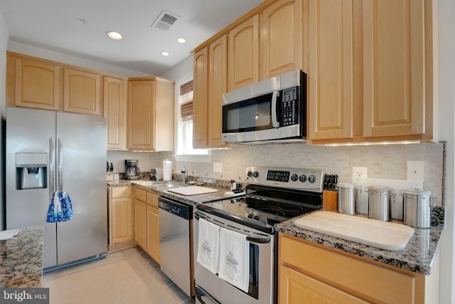 kitchen featuring dark stone counters, appliances with stainless steel finishes, visible vents, and light brown cabinets