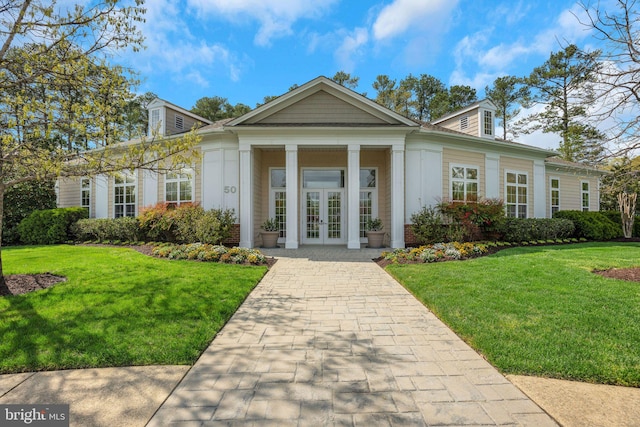 view of front of property with french doors, brick siding, and a front yard