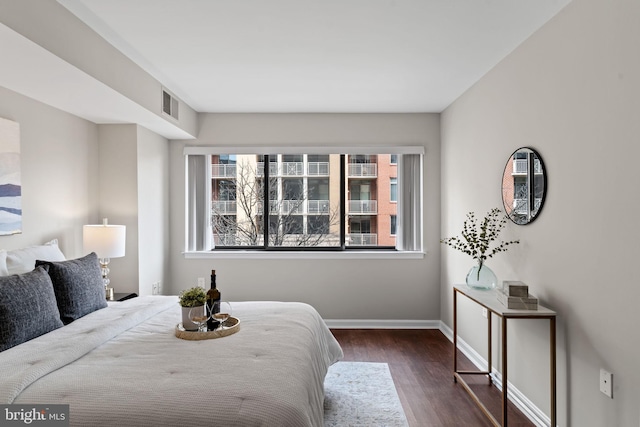 bedroom featuring visible vents, baseboards, and wood finished floors