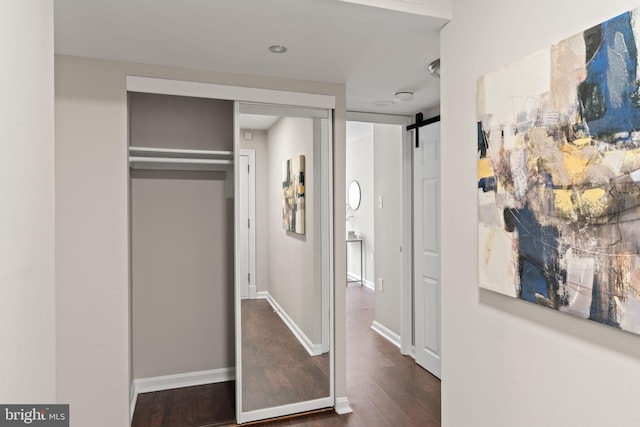 interior space featuring baseboards, a barn door, and wood finished floors