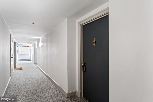 corridor with baseboards and carpet flooring