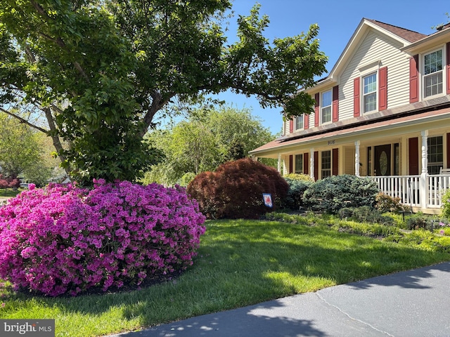 view of property exterior with a porch and a lawn