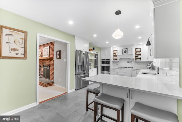 318 Longwood Rd, Kennett Square, PA 19348 - kitchen with stainless steel appliances, a sink, a peninsula, a fireplace, and white cabinets