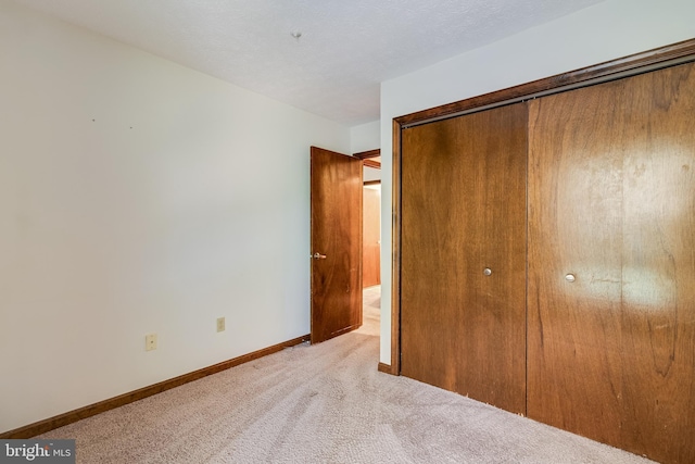 unfurnished bedroom featuring baseboards, light colored carpet, and a closet