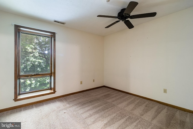 spare room with carpet floors, ceiling fan, visible vents, and baseboards