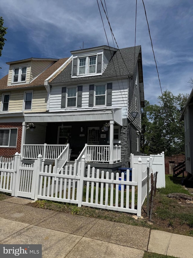 view of front of house with a porch, a shingled roof, and a fenced front yard