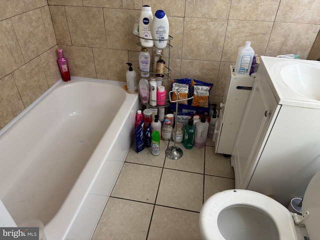 full bathroom with vanity, toilet, tile patterned floors, a washtub, and tile walls