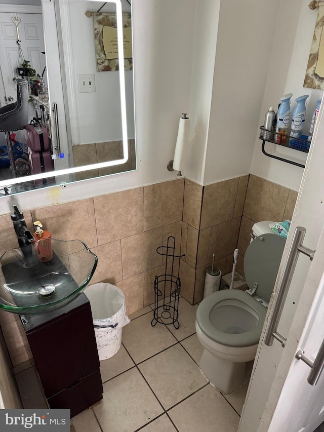 half bathroom featuring tile walls, a sink, a wainscoted wall, tile patterned floors, and toilet