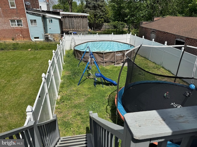 view of yard with a fenced in pool, a fenced backyard, and a trampoline