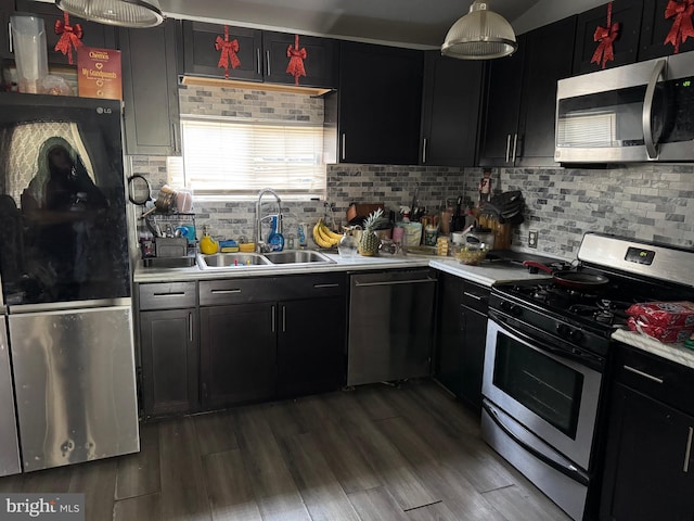 kitchen featuring light countertops, appliances with stainless steel finishes, a sink, and tasteful backsplash