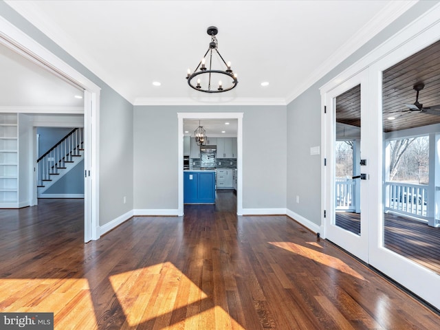 unfurnished dining area featuring crown molding, a notable chandelier, stairs, baseboards, and dark wood-style floors