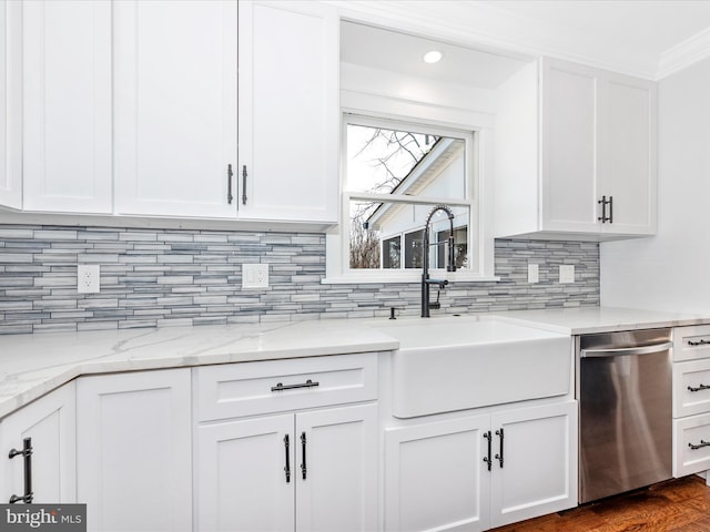 kitchen featuring stainless steel dishwasher, white cabinets, a sink, and tasteful backsplash