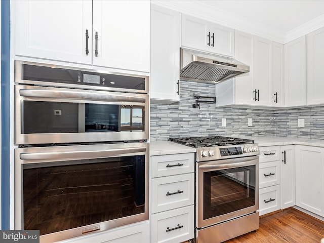 kitchen featuring white cabinetry, appliances with stainless steel finishes, under cabinet range hood, and tasteful backsplash