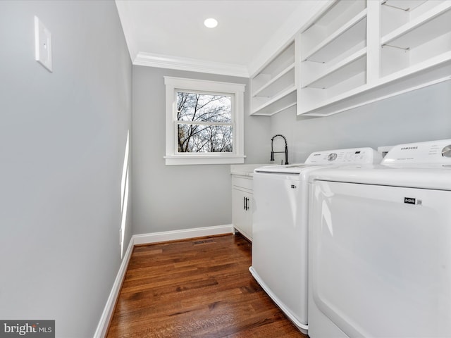washroom with cabinet space, separate washer and dryer, baseboards, dark wood-type flooring, and ornamental molding